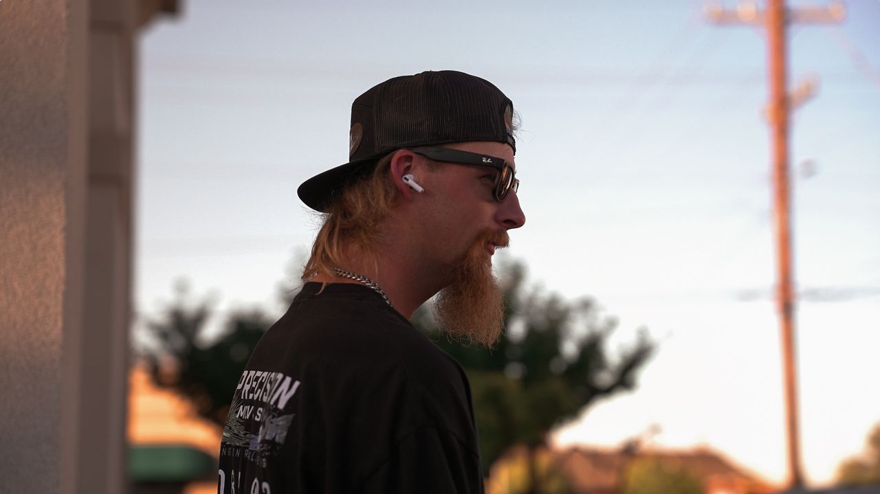 Crew member in a backwards cap and Precision shirt in profile at golden hour